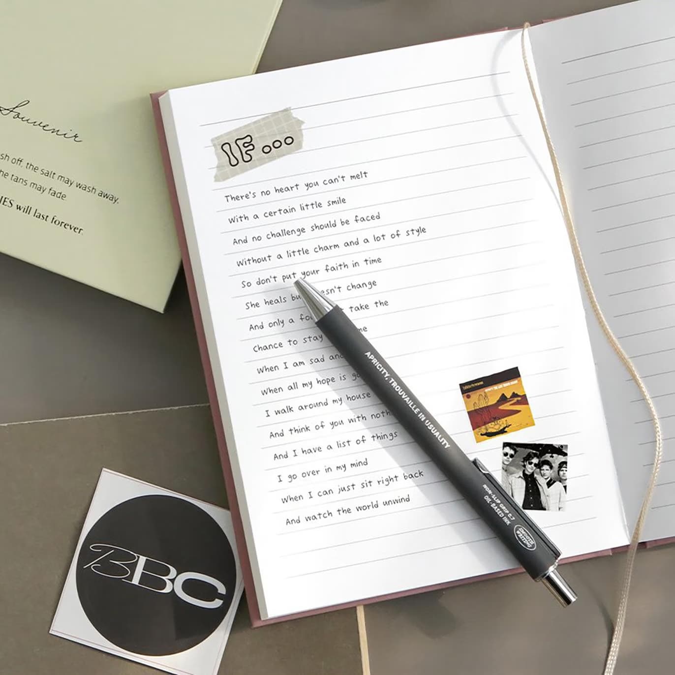 An open journal featuring handwritten poetry, a pen, and decorative stickers on the page.